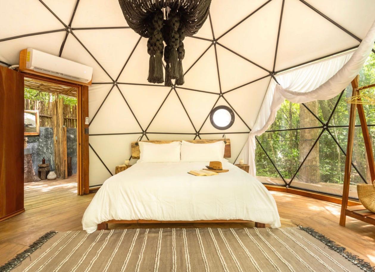 Domo con cama king y ventanal a la selva